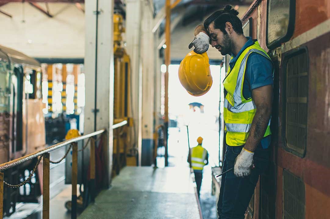 A guy wiping his brow while working in a heated work area
