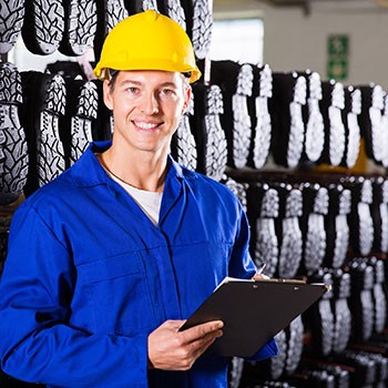 Worker with clipboard and rack of safety boots